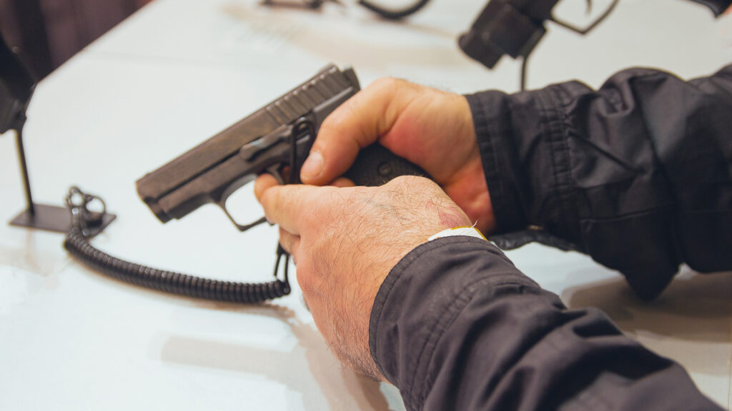 man holding gun to purchase at counter of gun store